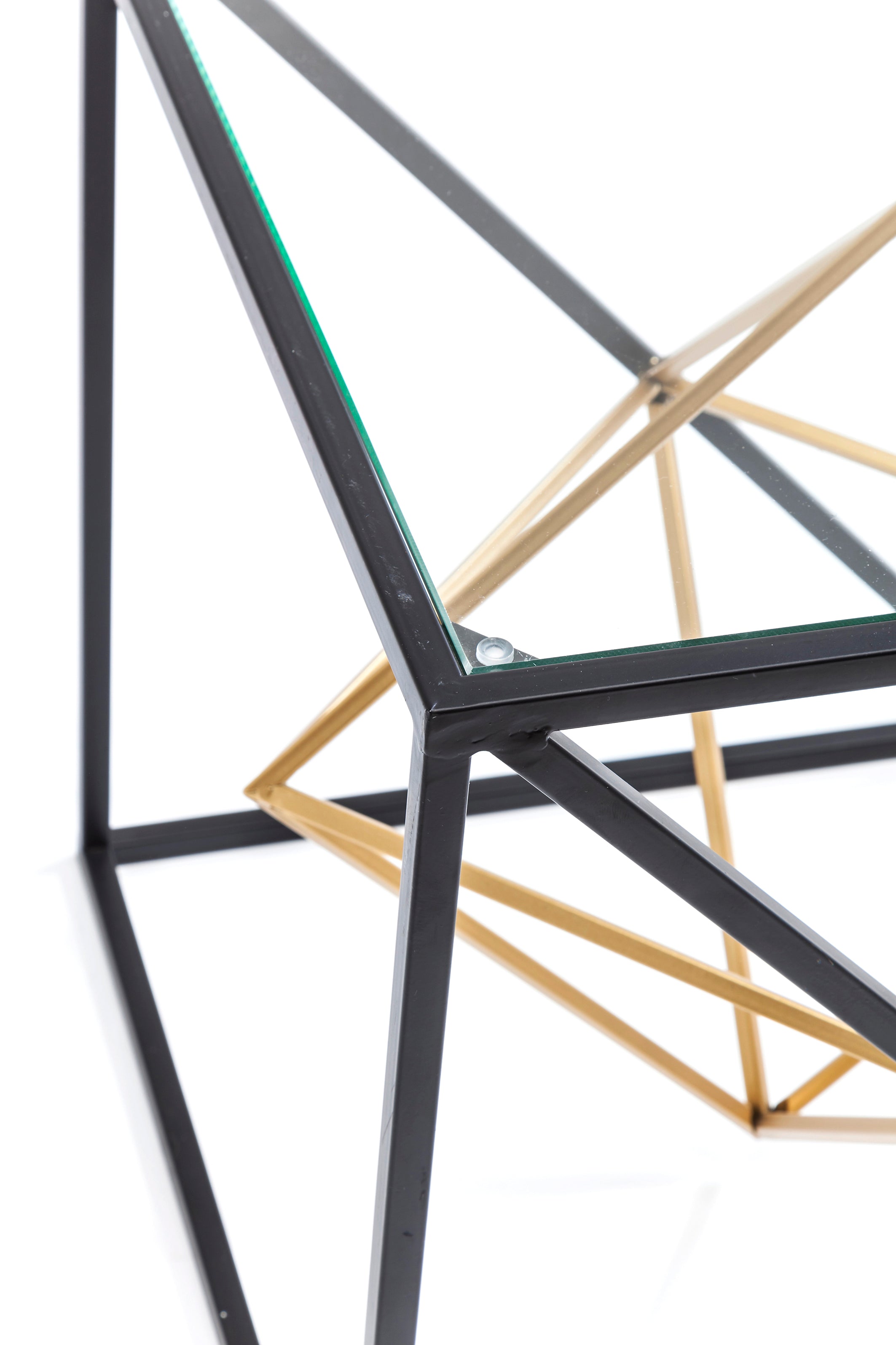 Nahaufnahme des Beistelltischs Prisma, einem modernen quadratischen Beistelltisch mit einem geometrischen schwarz-goldenen Metallrahmen mit sich kreuzenden Linien und einem minimalistischen Designermöbel-Look.