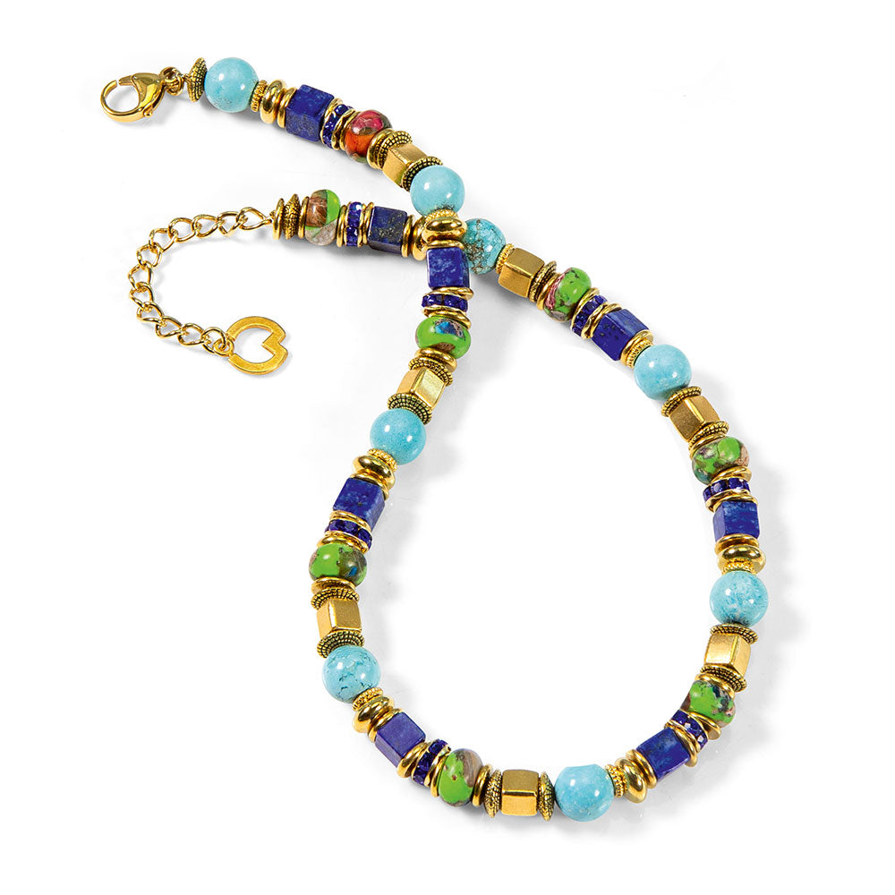 Petra Waszak: Collier „Casablanca“ – eine Perlenkette mit blauen, grünen und goldenen Perlen, goldenen Akzenten und einem herzförmigen Verschluss auf weißem Grund.