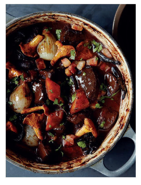 Ein Topf mit Rindereintopf mit Pilzen, Zwiebeln und Kräutern in einer reichhaltigen, dunklen Soße.