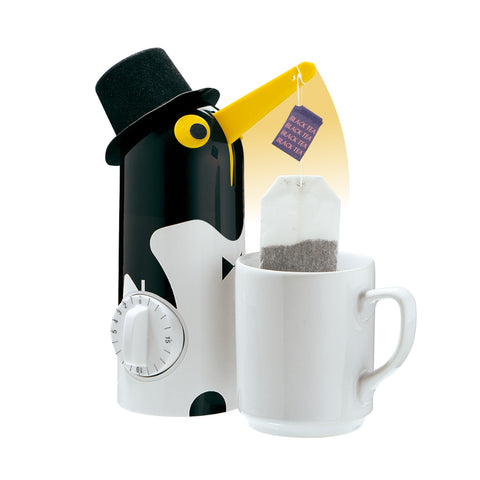 Ein pinguinförmiger Teekessel mit Hut gießt Tee in eine Tasse mit einem Teebeutel darin.