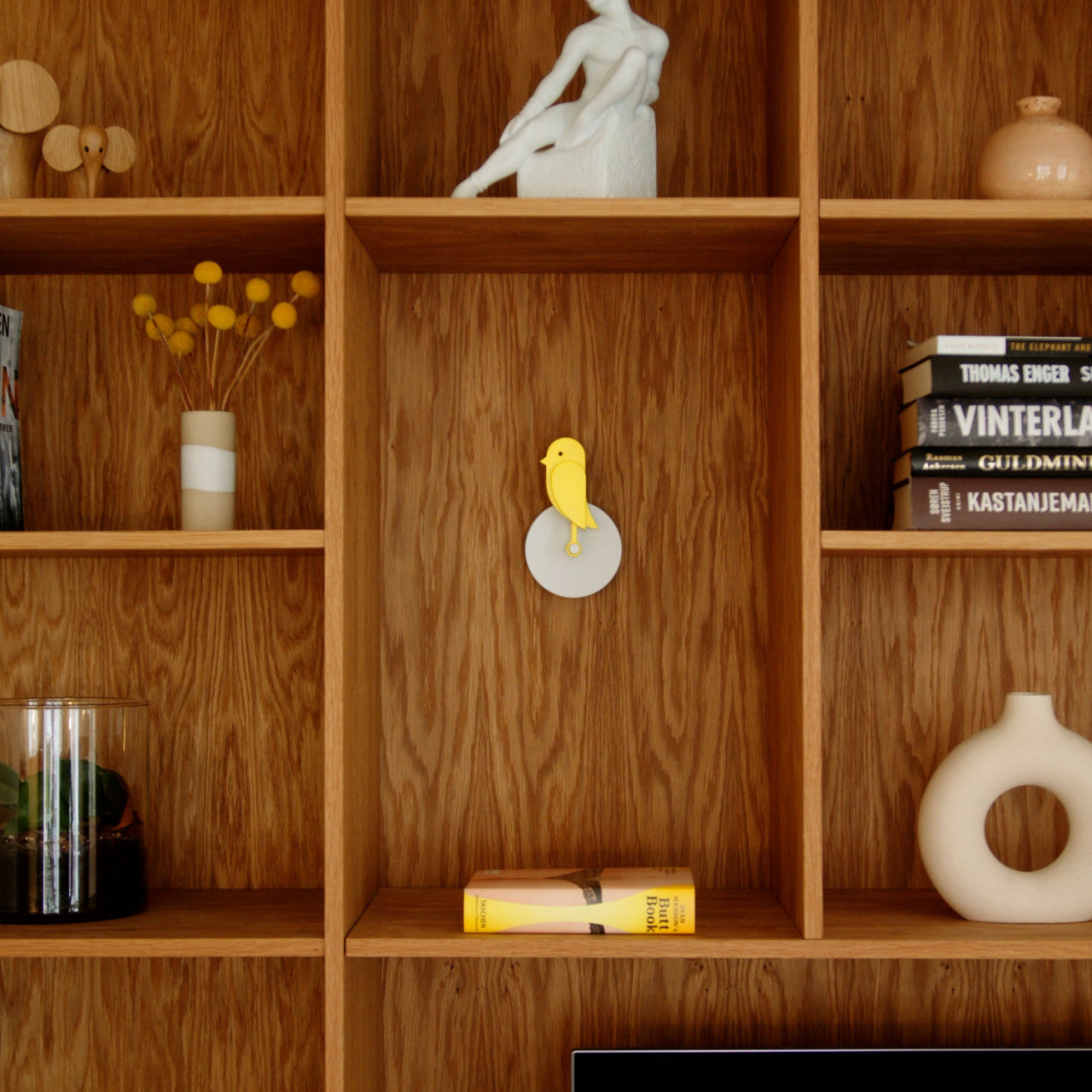 Holzregale mit Dekor, Büchern und einem Frischluftmonitor Birdie 2.0 mit CO2-Sensor, der an der Mittelplatte montiert ist.