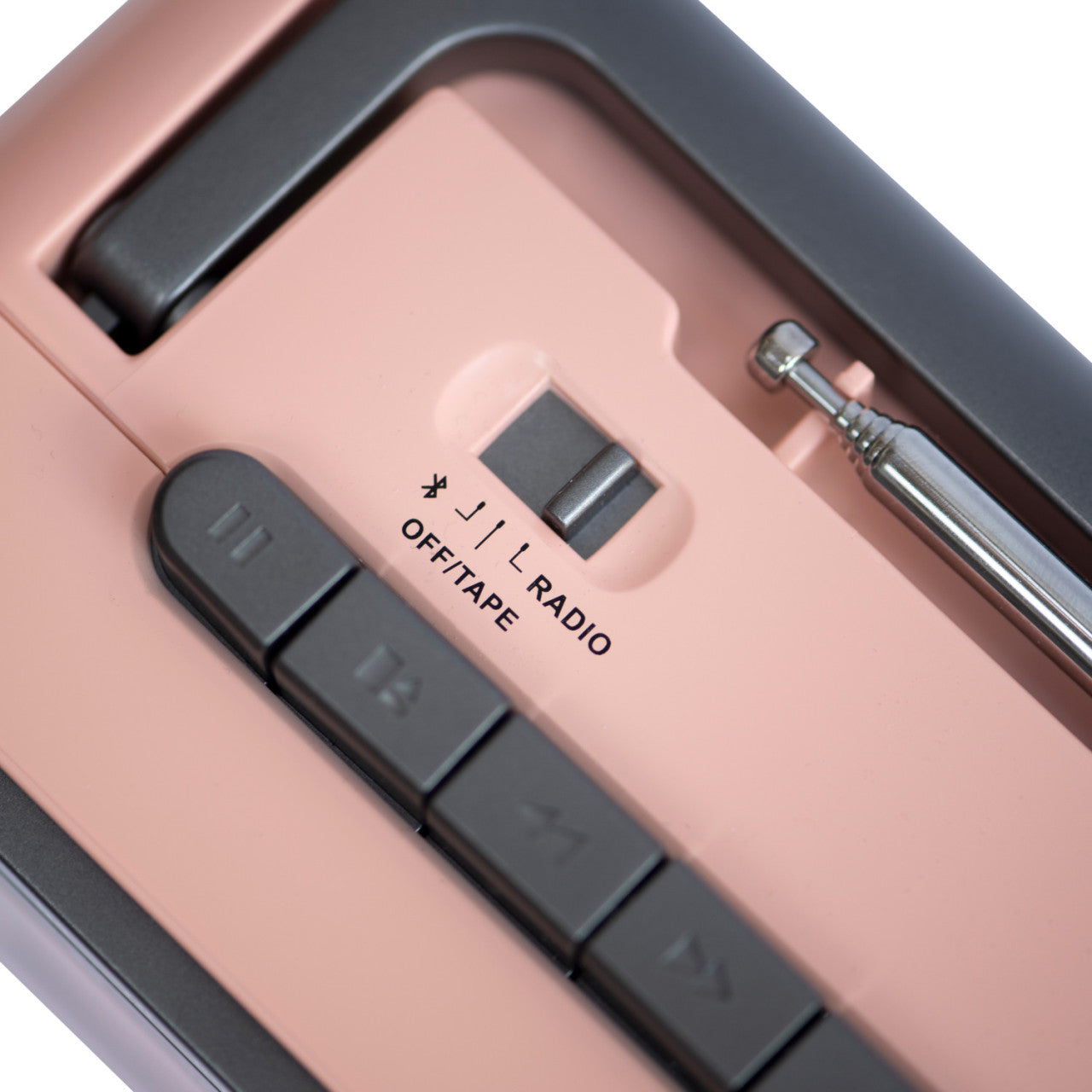 Nahaufnahme des Crosley Kassettenspielers in Rose/Grau mit Knöpfen, einem Schalter und einer sichtbaren Metallantenne.
