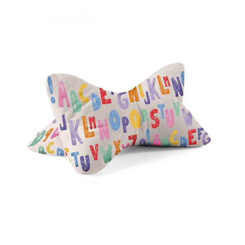 Kissen in Knochenform mit bunten Buchstaben des Alphabets in Großbuchstaben auf einem weißen Hintergrund.