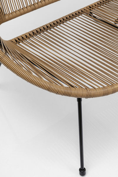 Eine Nahaufnahme eines geflochtenen Rattanstuhls mit schwarzen Metallbeinen, fotografiert vor einem schlichten weißen Hintergrund.