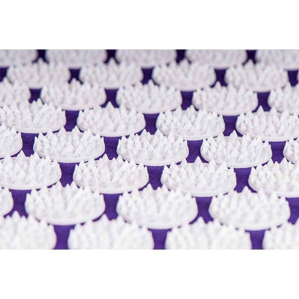 Nahaufnahme mehrerer weißer Plastikstacheln, die in kreisförmigen Mustern auf einer violetten Fläche angeordnet sind.