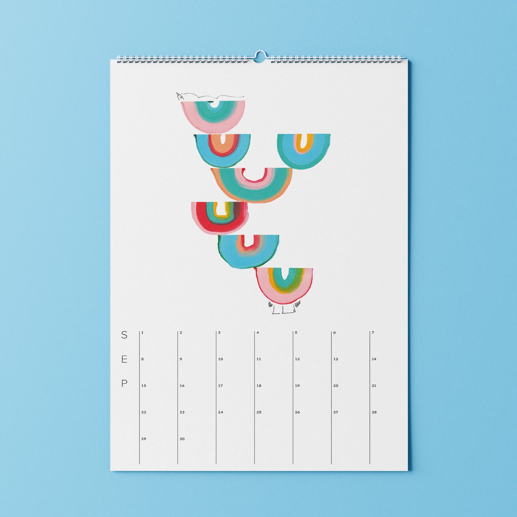 Minimalistischer Septemberkalender mit bunten Regenbogenbögen oben, der an einer hellblauen Wand hängt.