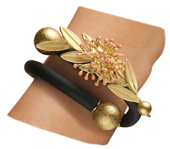 Gold-schwarzes Armband mit Blumen- und Blattmuster und rosa Akzenten an einem Handgelenk.