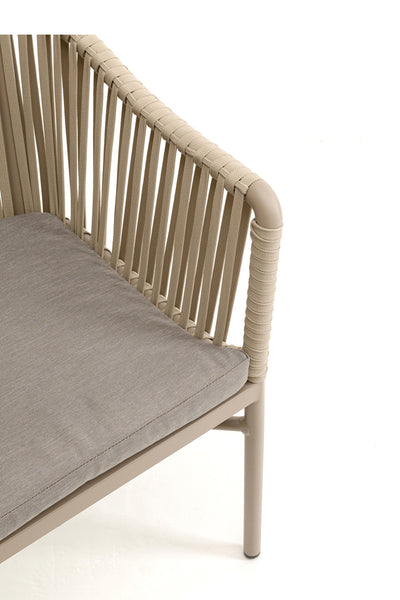 Nahaufnahme eines beigen Outdoor-Stuhls mit seilumwickelter Armlehne und vertikaler Seilrückenlehne, mit grau gepolstertem Sitz auf hellem Hintergrund.