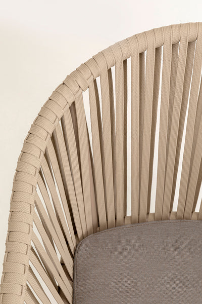 Nahaufnahme eines beigen Stuhls mit vertikalen geflochtenen Bändern als Rückenlehne und gepolstertem Sitz.