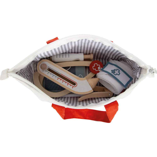 Draufsicht auf eine geöffnete medizinische Spielzeugtasche, die ein Spielzeugthermometer, eine Spritze, einen Verband und andere medizinische Instrumente aus Holz enthält.