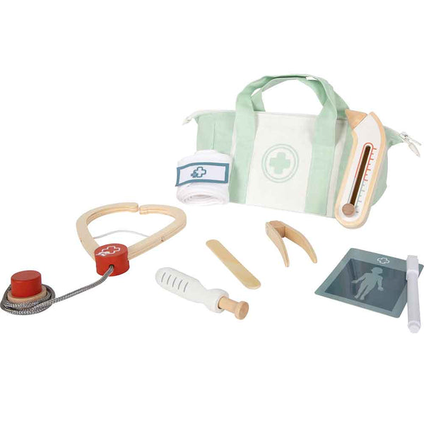 Ein Spielzeug-Arztkoffer mit einer grün-weißen Tasche, einem Stethoskop, einem Thermometer, einem Reflexhammer, einer Spritze, einem Holzstab, einem Verband, einem Röntgenbild und einem Stift auf einer weißen Fläche.