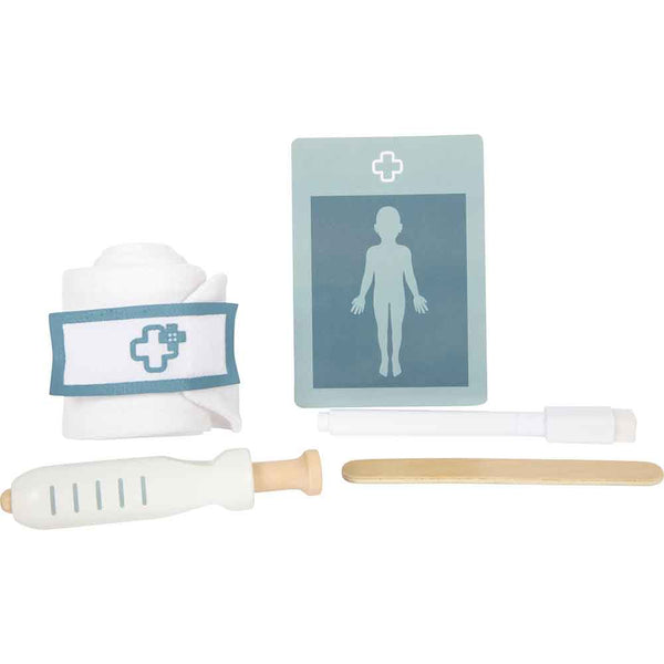 Ein medizinisches Spielzeugset mit einem Verband, einem Krankenblatt, einer Spritze, einem Zungenspatel und einem Reflexhammer, die alle auf einem weißen Hintergrund angeordnet sind.