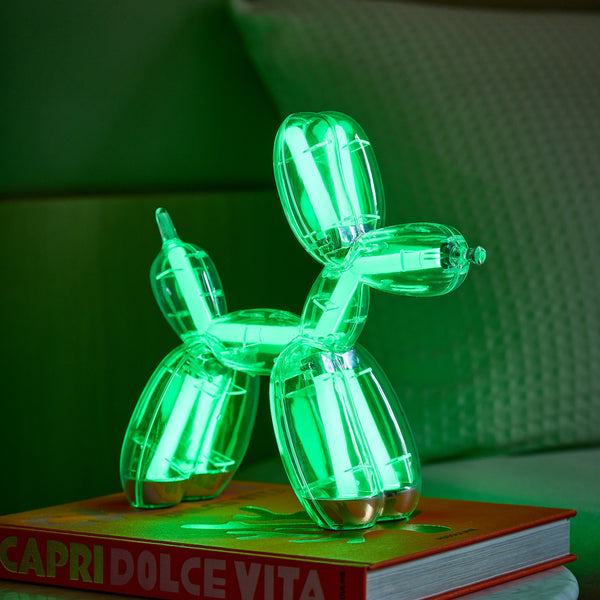 Eine grüne Ballonhund-Lampe leuchtet über einem orangefarbenen Buch mit dem Titel CAPRI DOLCE VITA.