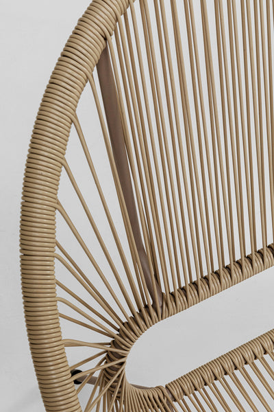 Nahaufnahme einer modernen Bank mit rundem Gestell und dicht geflochtenem hellbraunem Rattan- oder Flechtmuster vor einem schlichten weißen Hintergrund.