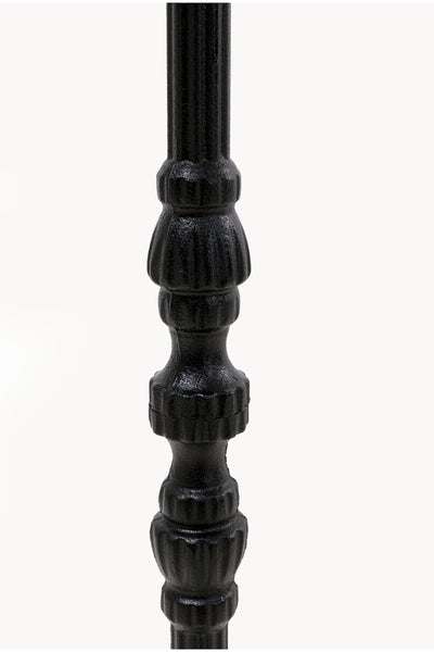 Nahaufnahme einer schwarzen, vertikal ausgerichteten Metallstange mit dekorativen, gerippten Details vor einem schlichten weißen Hintergrund.