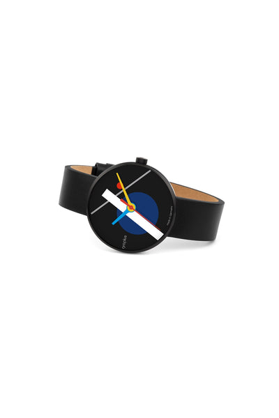 Eine Armbanduhr mit schwarzem Lederarmband und schwarzem Zifferblatt mit geometrischen Formen in Blau, Weiß und Rot, mit gelbem Stunden- und weißem Minutenzeiger.
