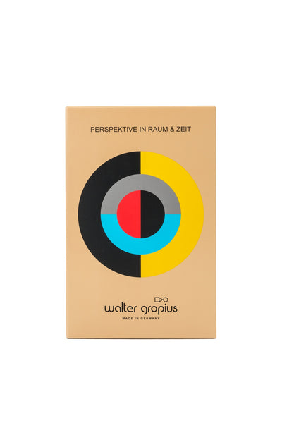 Eine beigefarbene, rechteckige Schachtel mit einem geometrischen Kreismuster in Schwarz, Gelb, Blau, Grau und Rot, beschriftet mit Perspektive in Raum & Zeit und Walter Gropius Made in Germany.