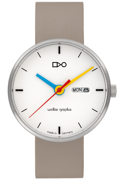 Eine Armbanduhr mit beigem Armband, weißem Zifferblatt, schwarzen Indexen, bunten Zeigern, Datums- und Tagesanzeige und Walter Gropius-Text auf dem Zifferblatt.