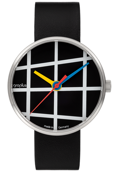 Eine Armbanduhr mit schwarzem Lederband, schwarzem Zifferblatt mit weißen, sich kreuzenden Linien und gelben, roten und blauen Zeigern. Auf dem Zifferblatt sind die Worte gropius und made in Germany zu lesen.