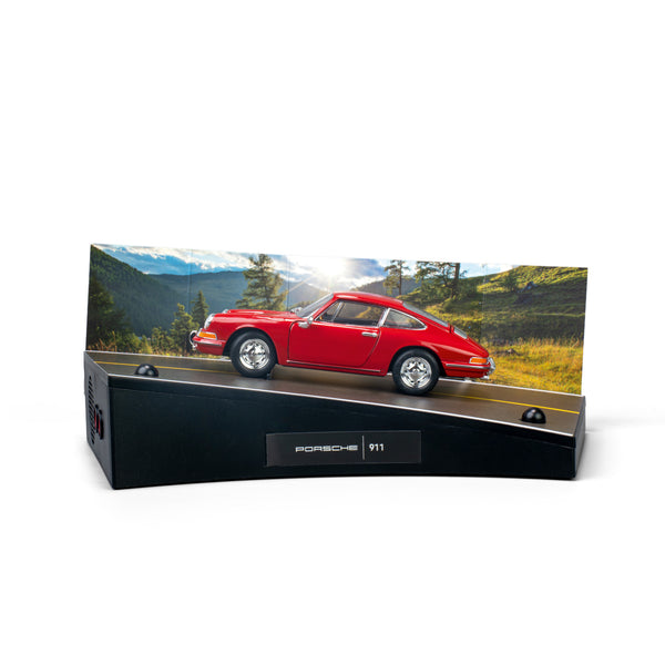 Ein rotes Porsche 911-Modell auf einem Ständer mit einem malerischen Berghintergrund.