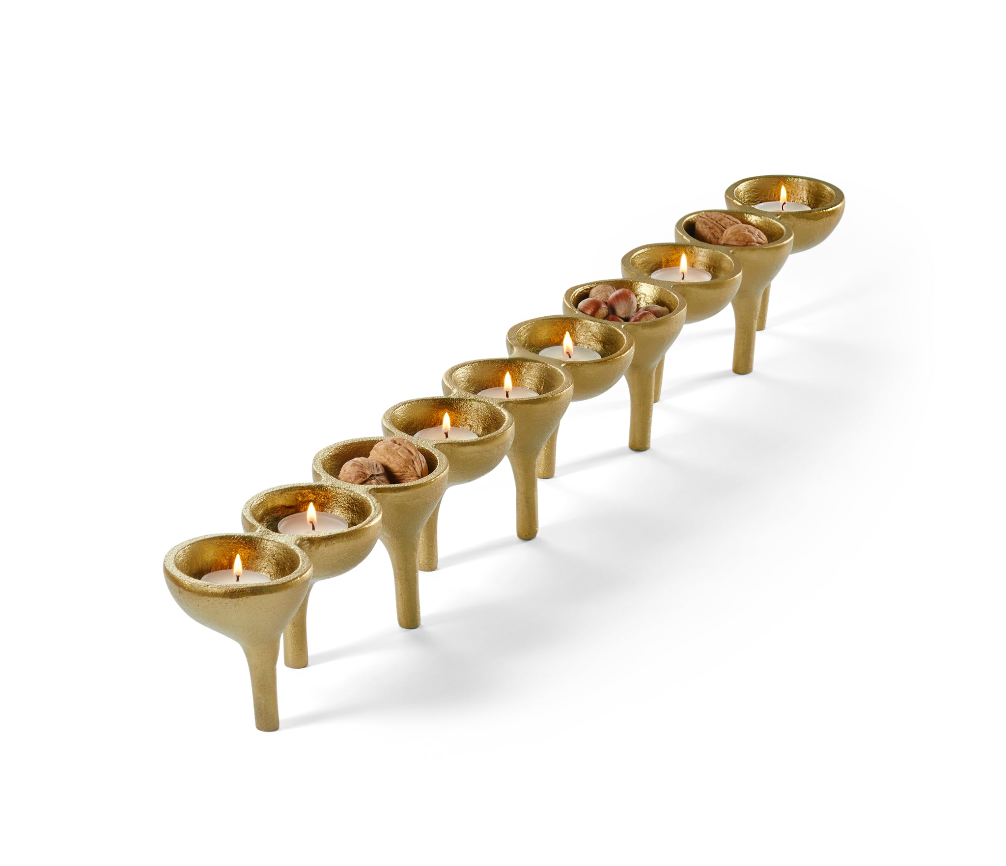 Eine moderne goldene Menora mit brennenden Kerzen und getrockneten Früchten in einigen Schalen, dargestellt auf einem weißen Hintergrund.