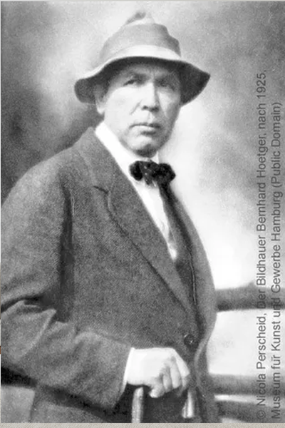 Schwarz-Weiß-Porträt eines Mannes in Anzug, Fliege und Hut, der mit einer Hand auf einem Stock steht; Stil des frühen 20.