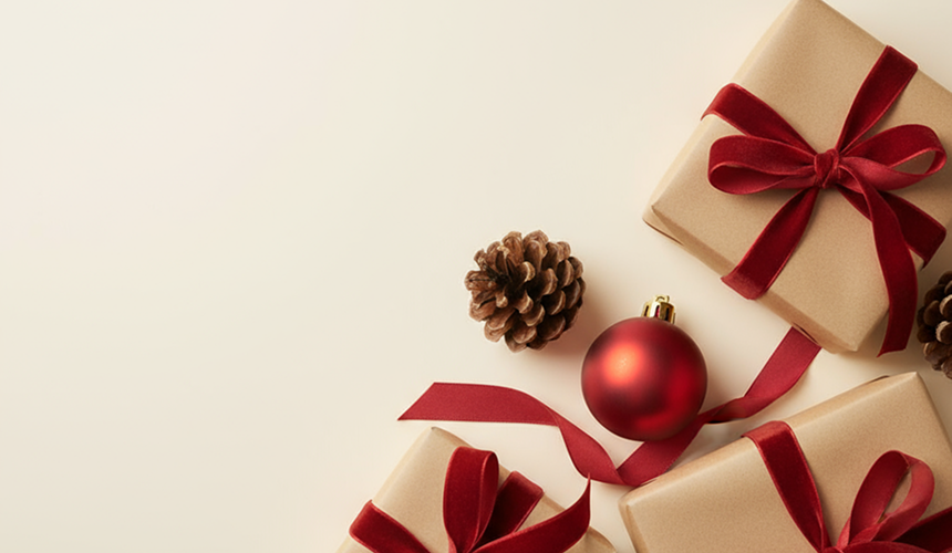 Geschenk mit rotem Schleifenband neben Tannenzapfen und roter Weihnachtsbaumkugel