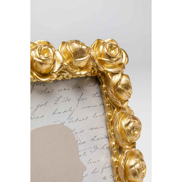 Nahaufnahme eines goldenen Bilderrahmens mit rosafarbenen Details, der einen handgeschriebenen Text und eine schwache Silhouette zeigt.