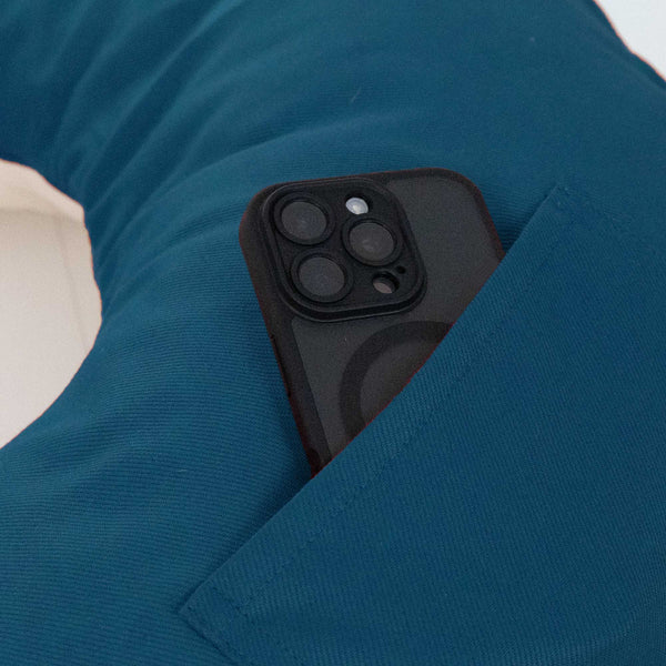 Ein schwarzes Smartphone in einer blaugrünen Tasche auf einem blauen Polster oder Kissen.