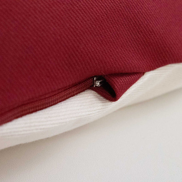 Nahaufnahme eines rot-weißen Stoffkissens mit einem teilweise sichtbaren Reißverschluss.