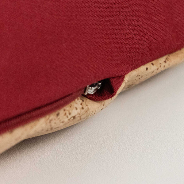 Nahaufnahme eines roten Stoffkissens mit sichtbarem Reißverschluss und korkartigem Rand auf einer weißen Fläche.