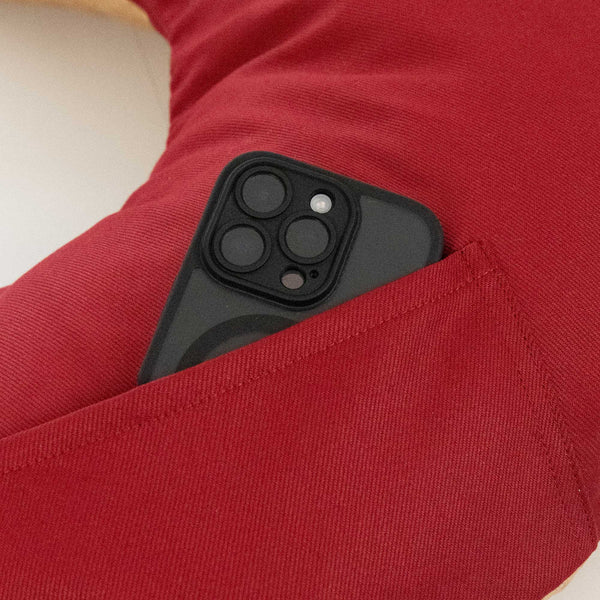 Ein schwarzes Smartphone, das teilweise in eine Tasche auf einer roten Stoffoberfläche gesteckt ist.