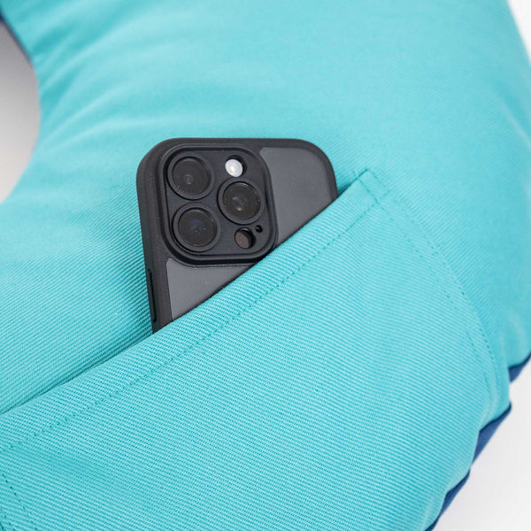 Ein schwarzes Smartphone in der Tasche eines türkisfarbenen Lese-kissens.