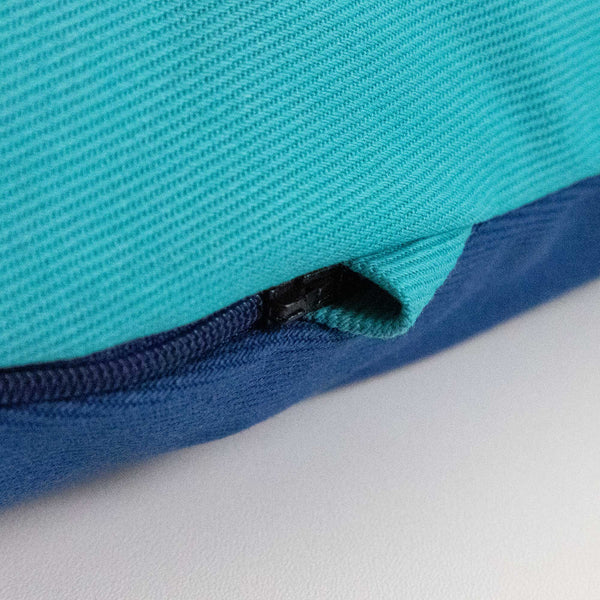 Nahaufnahme eines blauen und blaugrünen Stoffes mit einem teilweise sichtbaren schwarzen Reißverschluss entlang der Naht.