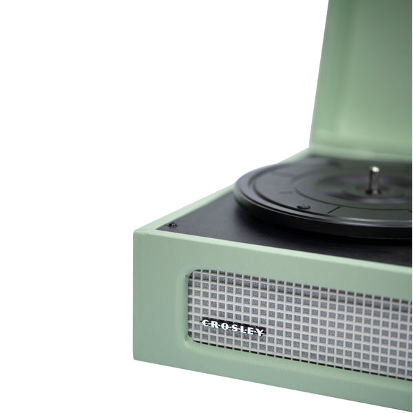 Nahaufnahme eines neuwertigen grünen Crosley-Plattenspielers mit geöffnetem Deckel, der einen Teil des Plattenspielers und der Lautsprecher zeigt.