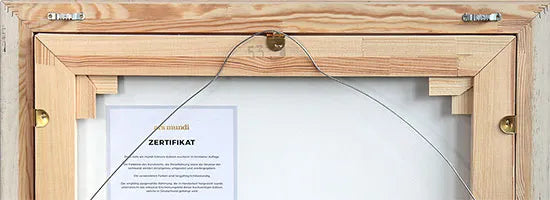 Die Rückseite eines hölzernen Bilderrahmens mit Aufhängedraht und einer teilweise sichtbaren Urkunde im Inneren.