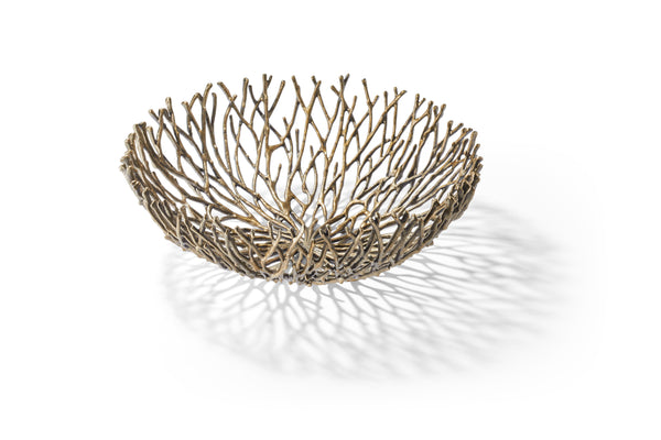 Dekorative Metallschüssel mit einem offenen, astähnlichen Muster, das auf weißem Hintergrund komplizierte Schatten wirft.