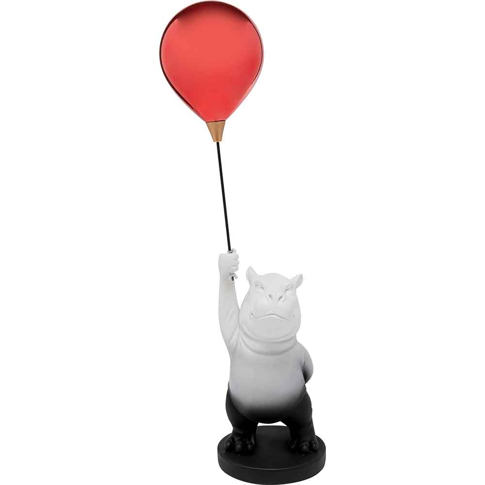 Graue Nilpferdfigur, die aufrecht steht und mit einem erhobenen Arm einen roten Luftballon an einem Stock hält.