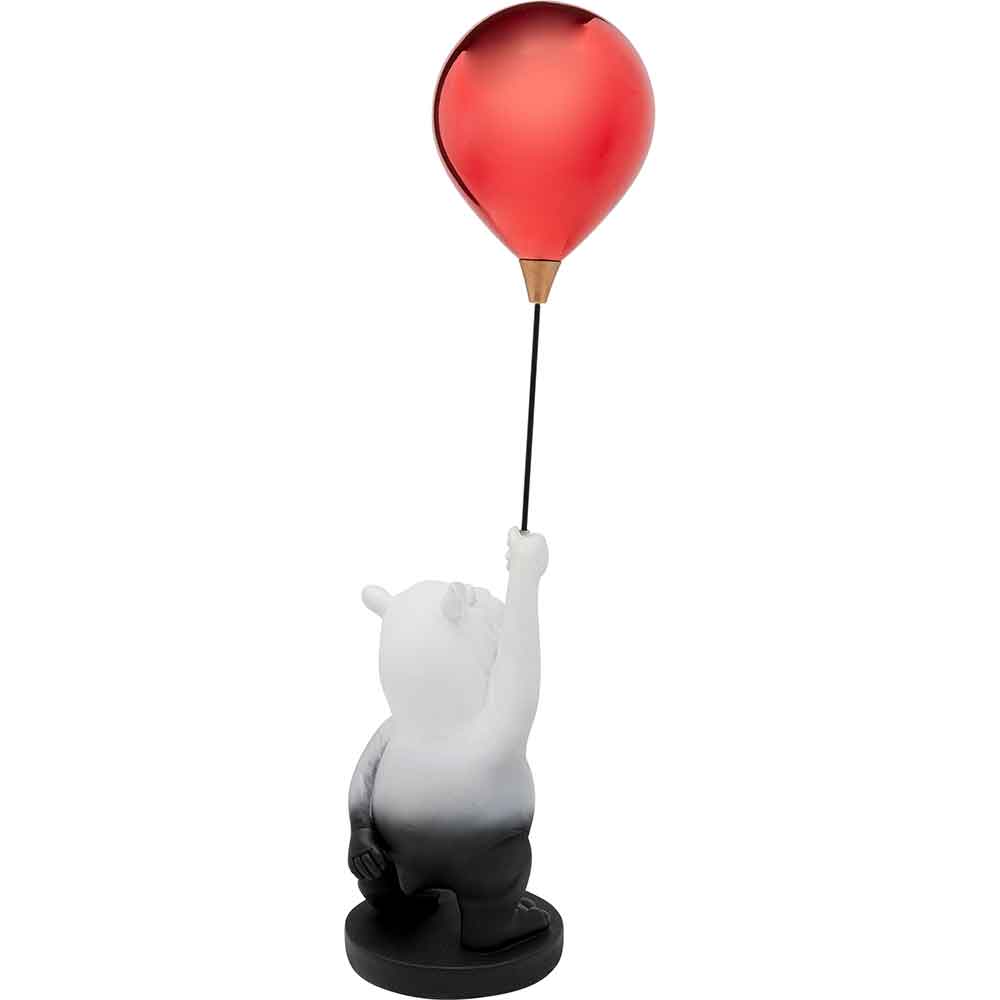 Eine Bärenfigur, die einen roten Luftballon in der Luft hält, steht auf einem runden schwarzen Sockel.