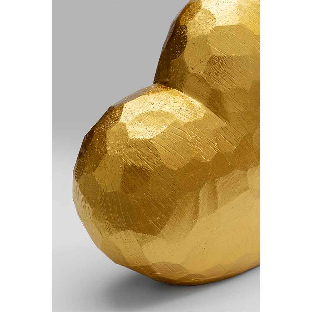 Nahaufnahme einer facettierten, metallischen Goldskulptur in Form eines Herzens vor grauem Hintergrund.