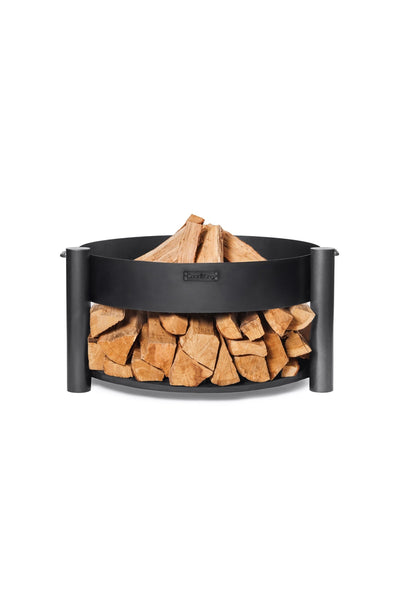 Ein schwarzer, runder Brennholzhalter aus Metall, der mit ordentlich gestapelten Brennholzscheiten gefüllt ist.