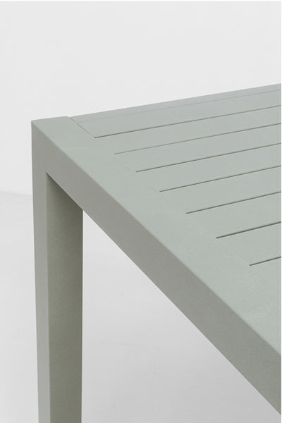 Nahaufnahme der Ecke eines modernen, rechteckigen, hellgrauen Metalltisches mit einer Lattenrostplatte.