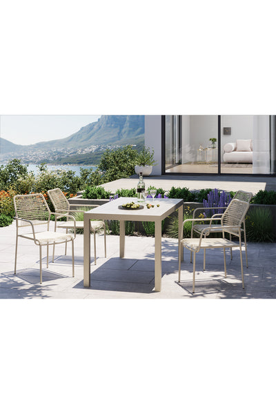 Terrassenset mit einem rechteckigen Tisch und vier Stühlen auf einer sonnigen Terrasse, mit Pflanzen in der Nähe und einer malerischen Aussicht auf Berge und Wasser im Hintergrund.