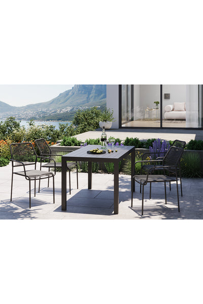 Ein modernes Terrassenset mit einem schwarzen Tisch und vier Stühlen auf einer Steinterrasse mit Blick auf eine malerische Landschaft mit Bergen und Wasser.