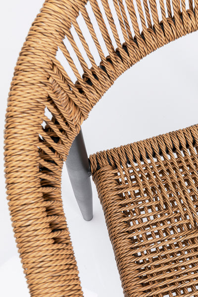 Nahaufnahme eines geflochtenen Rattanstuhls mit einem Metallbein, fotografiert von oben vor einem weißen Hintergrund.