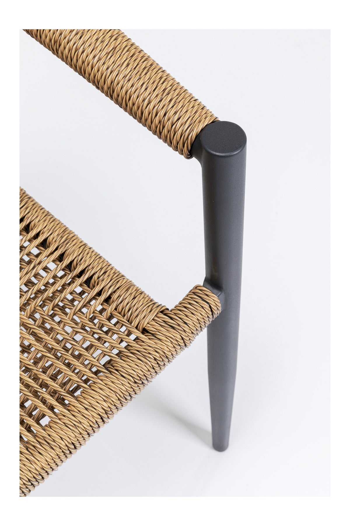 Nahaufnahme einer Stuhlecke mit Sitz und Rückenlehne aus geflochtenem Rattan, mit einem mattschwarzen Metallrahmen und -bein vor weißem Hintergrund.