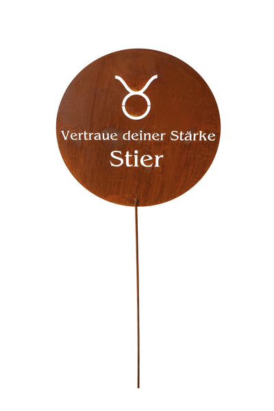 Rundes Holzschild mit weißem Taurus-Symbol und deutschem Text Vertraue deiner Stärke Stier auf einem dünnen Metallstab, isoliert auf weißem Hintergrund.