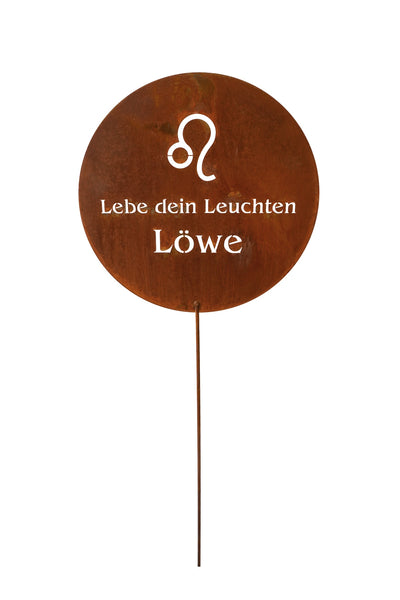 Ein rundes Gartenschild aus Metall mit dem Tierkreiszeichen Löwe und dem ausgeschnittenen deutschen Text Lebe dein Leuchten Löwe, montiert auf einem dünnen Stab.