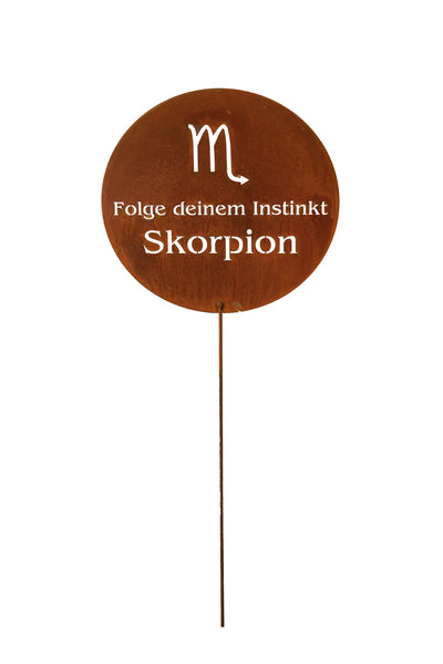 Ein rundes Metallschild auf einem Stock zeigt das Skorpion-Symbol und den deutschen Text Folge deinem Instinkt Skorpion auf einem weißen Hintergrund.