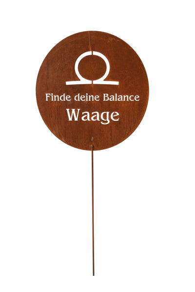Rundes braunes Schild mit dem Tierkreiszeichen Waage, deutschem Text Finde deine Balance und Waage, montiert auf einem dünnen Metallstab.